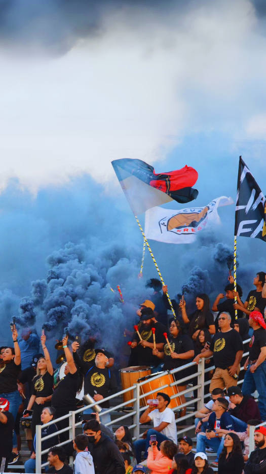 Fans at a Fresno Valley 559 FC Semi-Professional soccer games celebrate with smoke, drums, and cheering